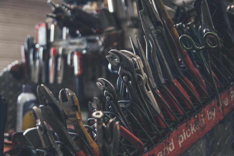 Close-up of a heat gun on a wooden workbench surrounded by nozzles and DIY materials